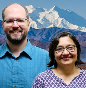 Uma an Peter smile at the camera in front of Denali.