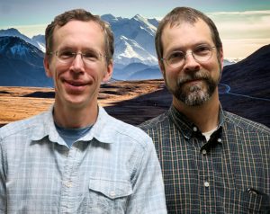 Kent and Scott smile in front of a snoy mountain.