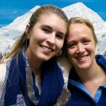 Megan and Sorina put their arms around each other in front of snowy mountains.