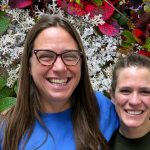 Jessica and Jessie smile in front of a bed of lichen and leaves.