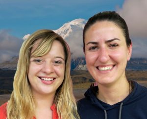 Two women stand close together, smiling in front of Denali.
