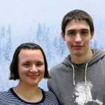 Carrie and Tristan lean together and look at the camera with snowy trees behind them.