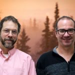 Scott and Bob smile in front of smokey trees.