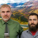 Bill and Nathan, two men with straight faces, stand in front of a colorful river, forest, and mountain.