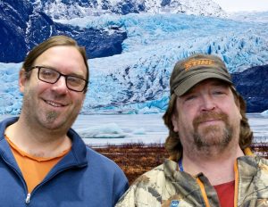 Lance and Ryan smile in front of a glacier calving front.