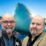 Fred and Kurt smile in front of a blue iceberg.