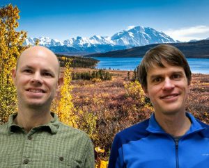 Eran and Gabe smile in front of a lake and mountains.