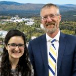 Dan and Diane, the chancellor and a student, smile at the camera in front of a photoshopped background of the University of Alaska campus.
