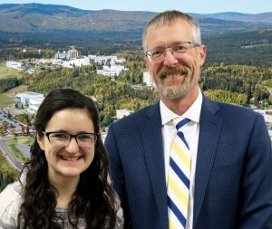Dan and Diane, the chancellor and a student, smile at the camera in front of a photoshopped background of the University of Alaska campus.