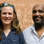 Jessie and Abraham smile at the camera in front of a photoshopped background of a grain field.